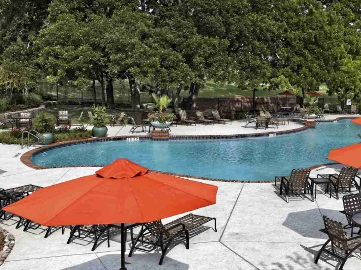 Resort style pool with chairs and umbrellas around the pool and lots of trees around the outside edge for article Tucker Hill for newcomers moving to DFW or moving within the Dallas-Fort Worth area.