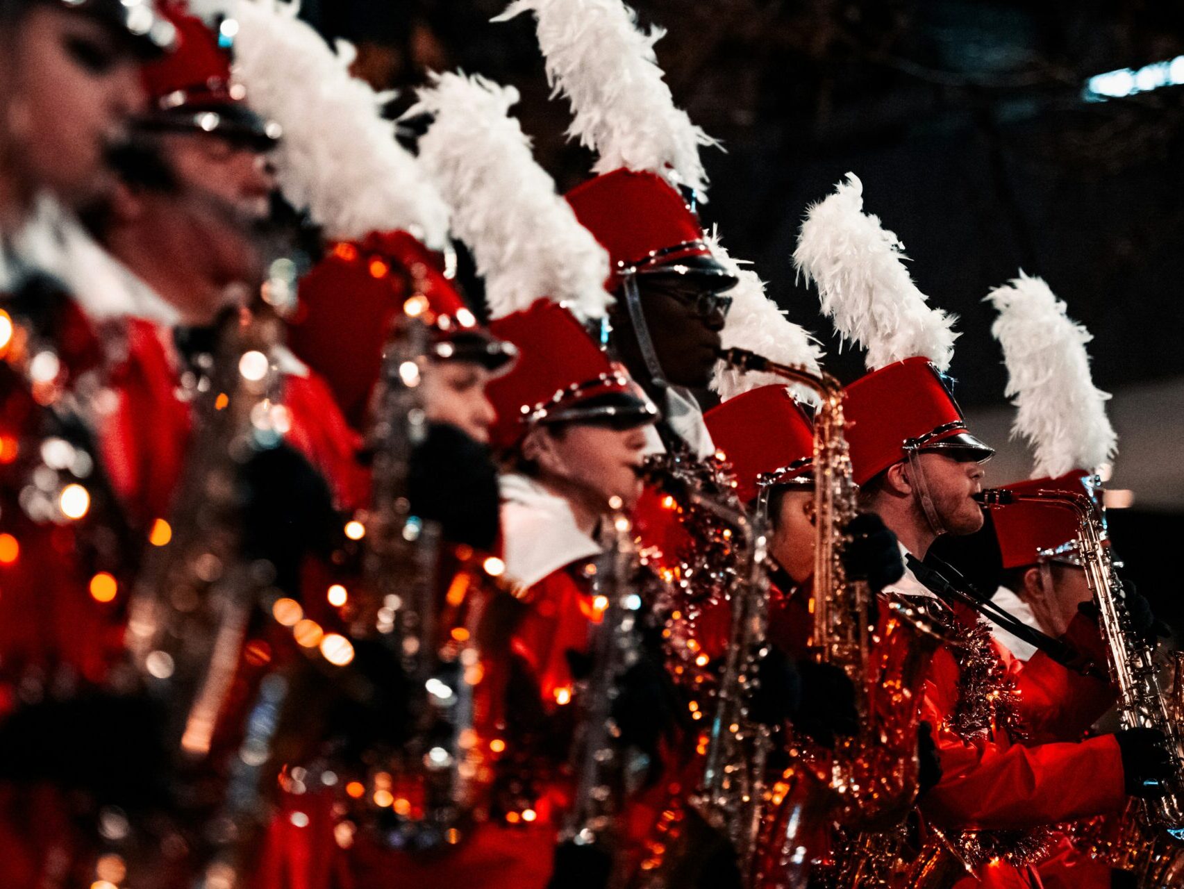 high school band performing with red uniforms and white feather hats