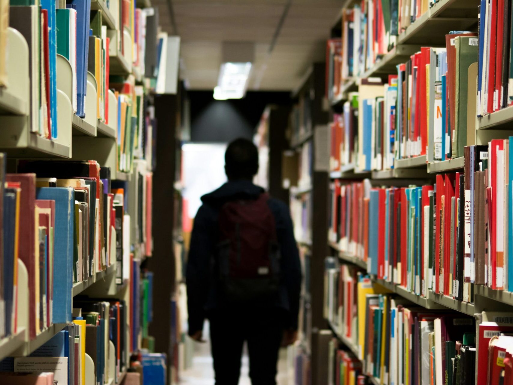 student walking through library with bookshelves on the right and left