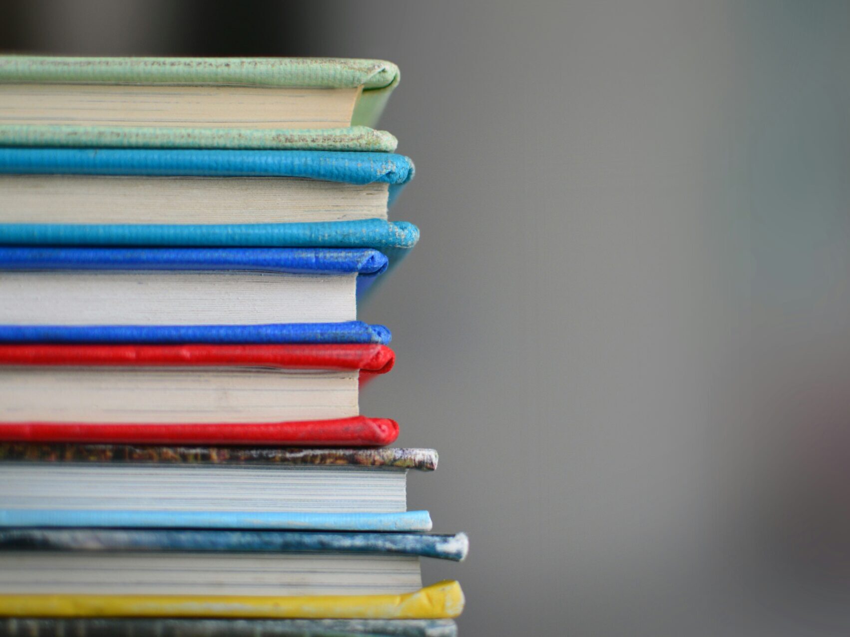 stack of colorful books with gray background