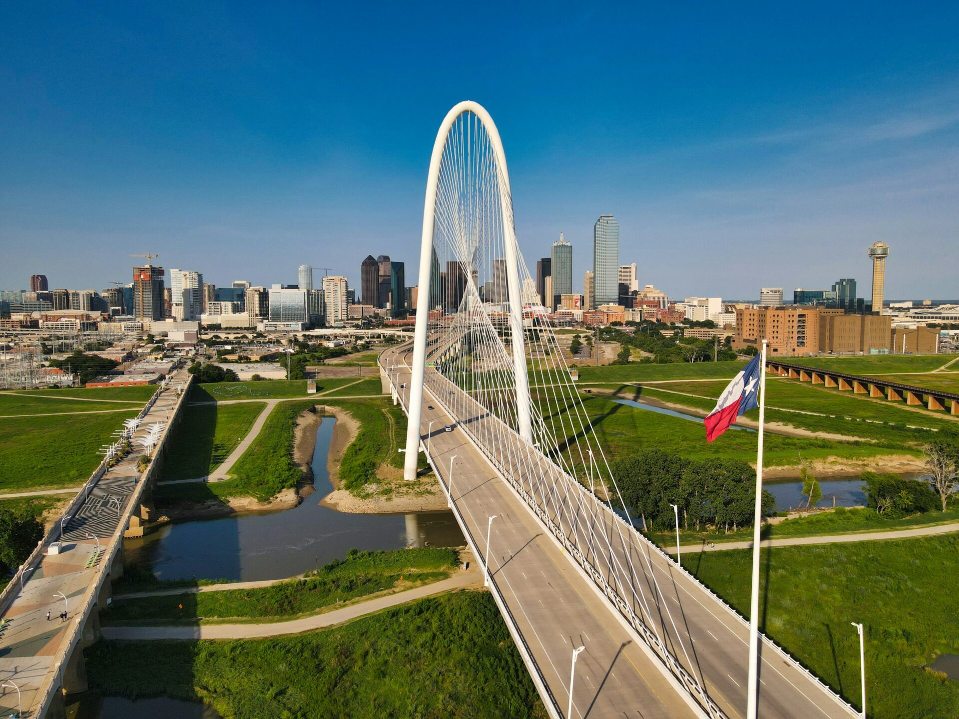 bridge in Dallas Texas with Texas flag in foreground and blue sky