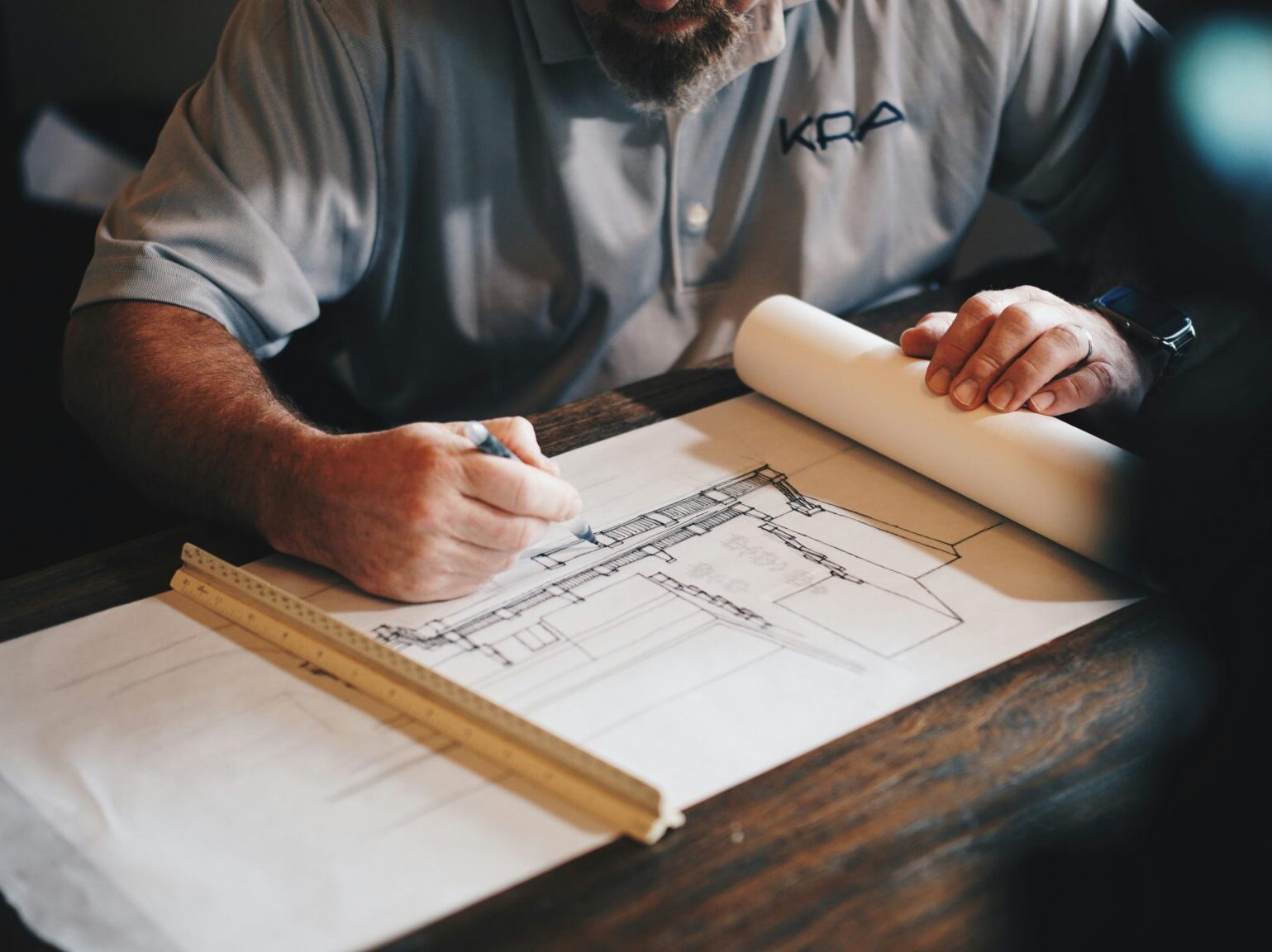 male at drafting table with building drawing