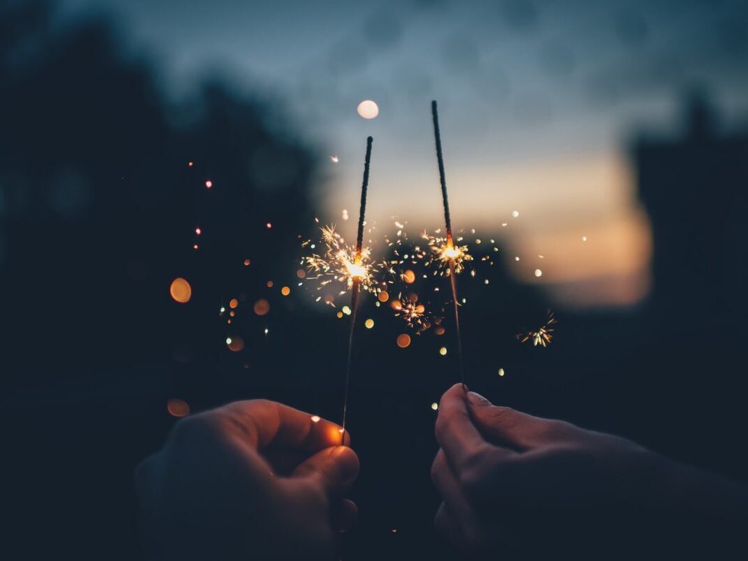 people holding sparklers at dusk