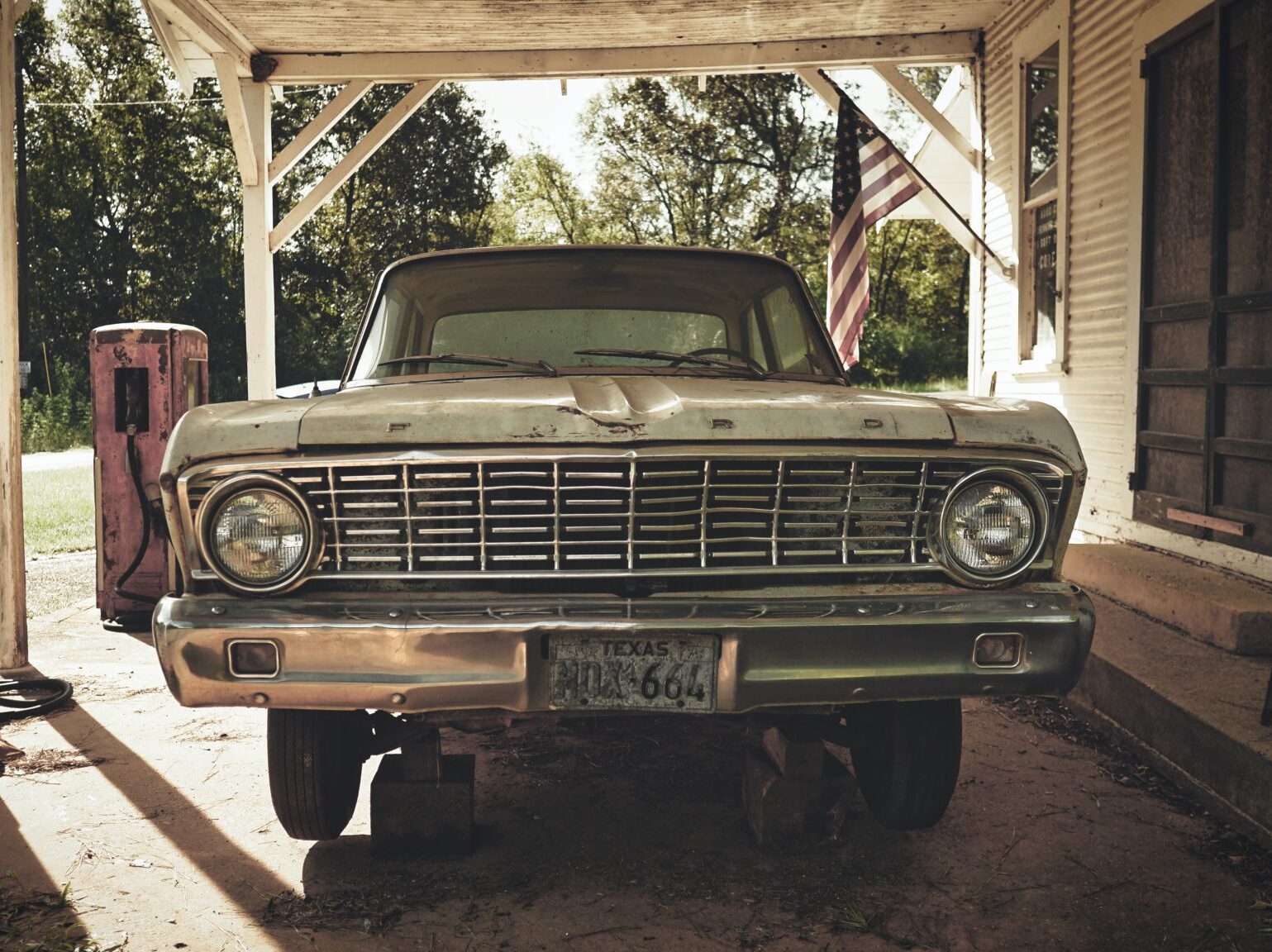 old truck in carport with American flag in background