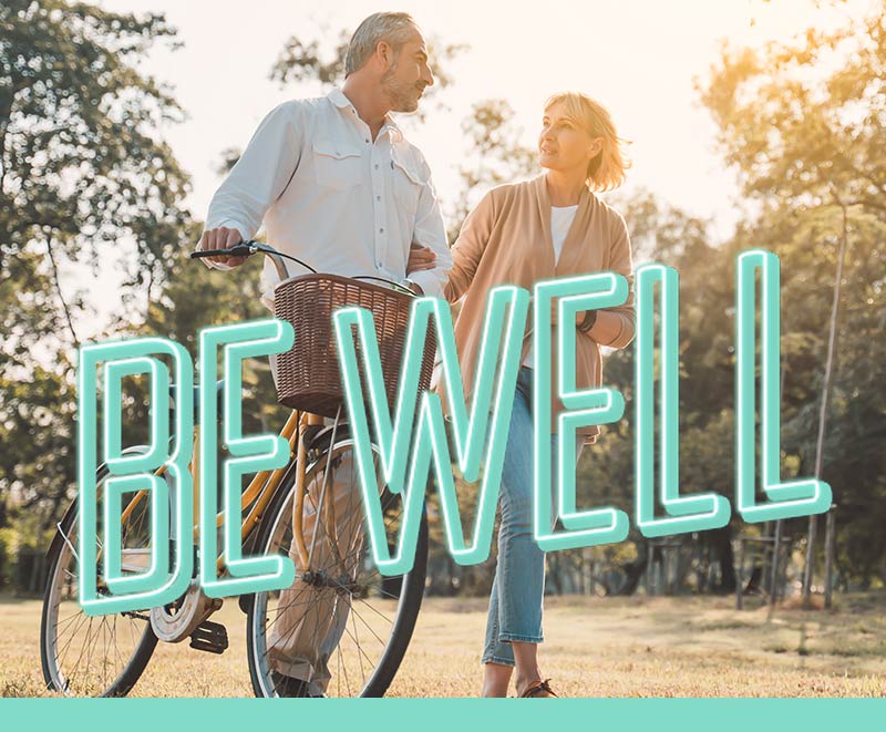 Man holding a bike and walking in park with a woman