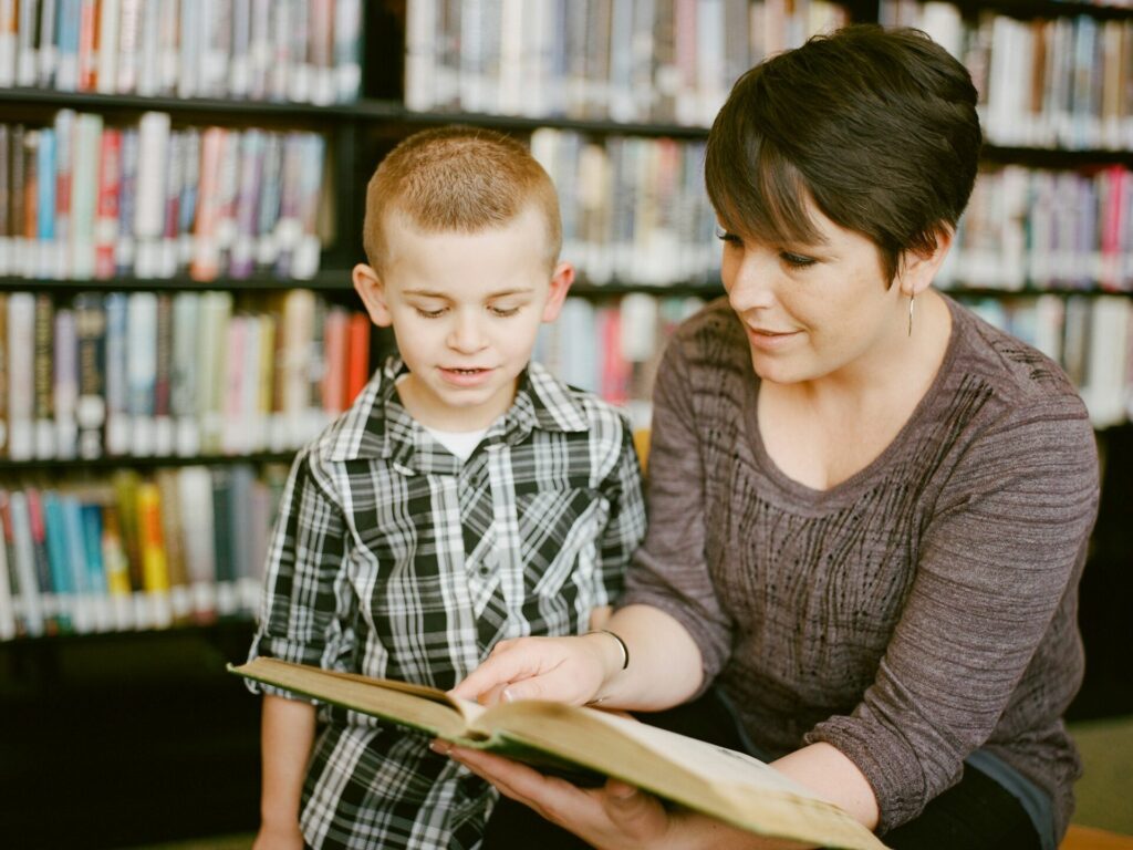 A teacher reading to her student one-on-one in a library