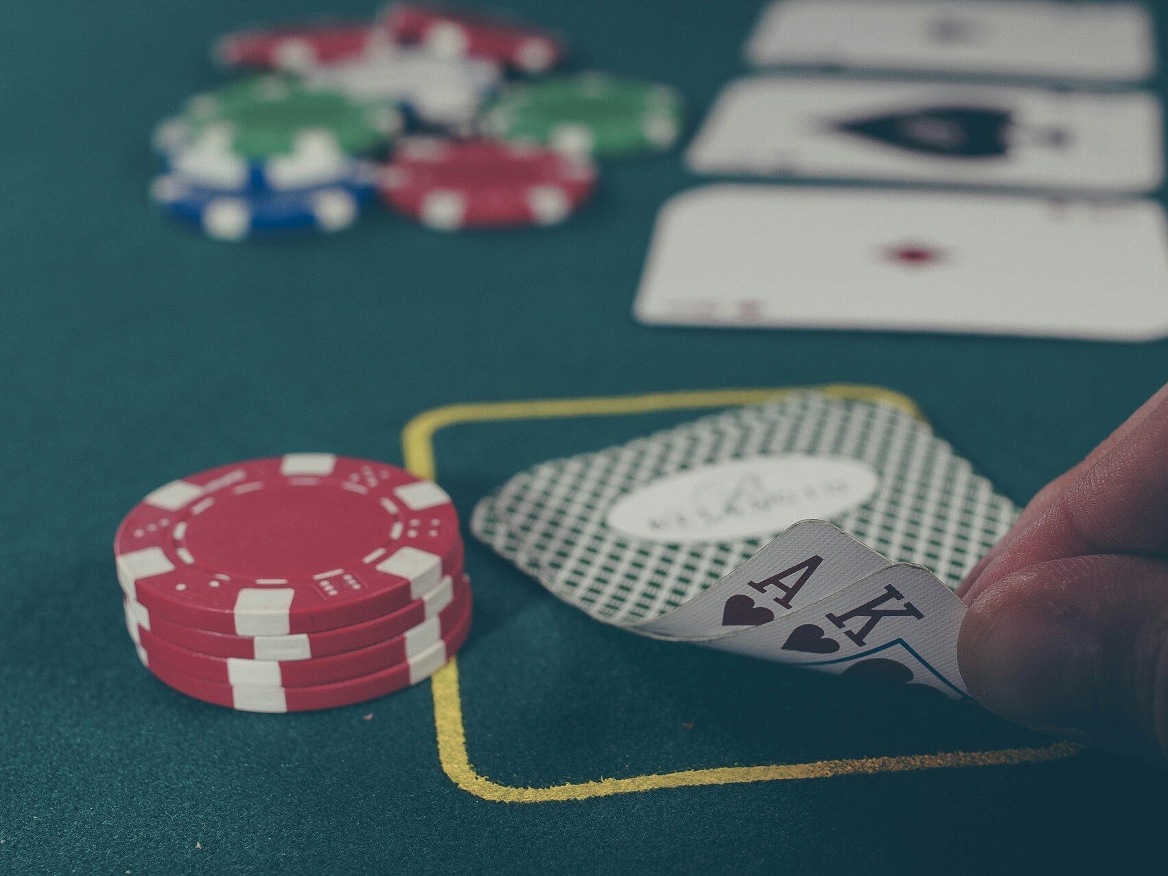 person holding A of spades and K of spades on a poker table with chips