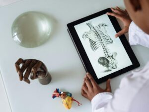 doctor looking at skeleton on ipad with orthopedic props on table