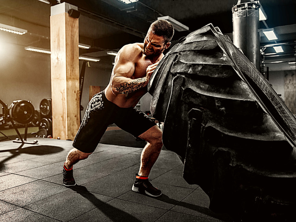 Man flipping large tire in CrossFit gym.