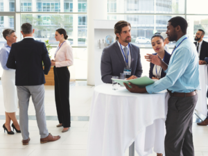 Diverse group of professionals standing around small tables chatting at a networking event
