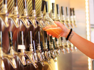 Wall of beer taps and one glass being filled.