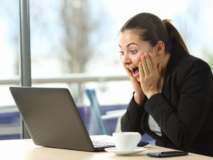 Person celebrating in front of computer after finding contract work online.