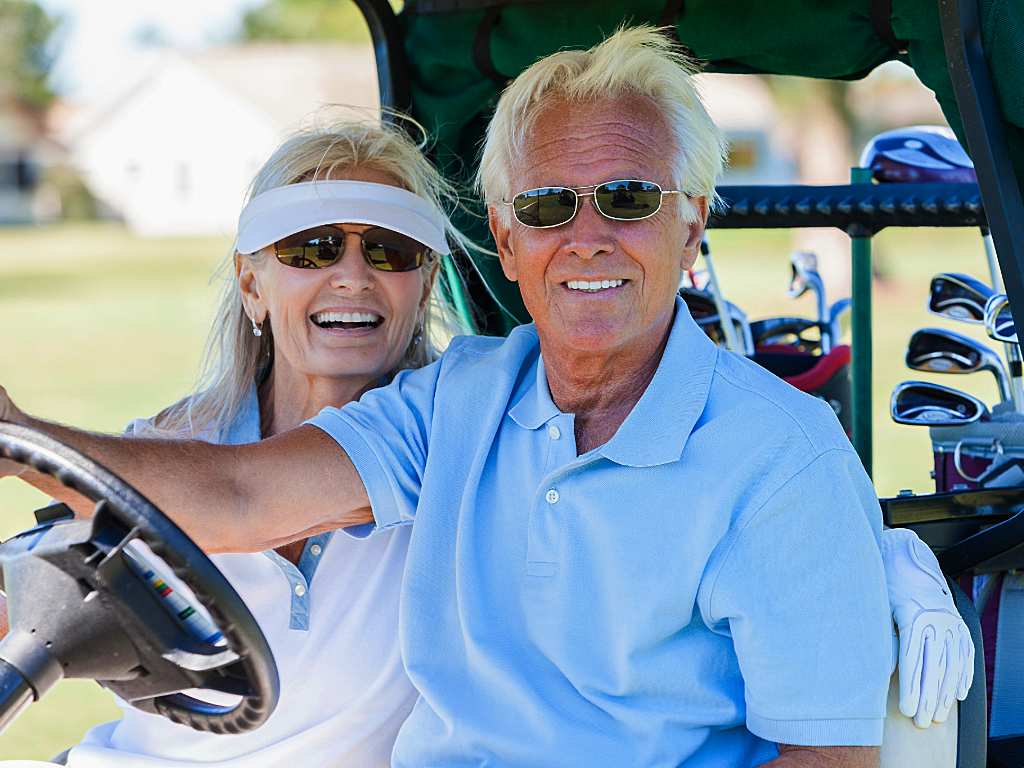 Senior couple sitting in golf cart smiling at camera for article Ultimate Retirement Paradise: Top 5 Golf Courses in DFW for newcomers moving to DFW.