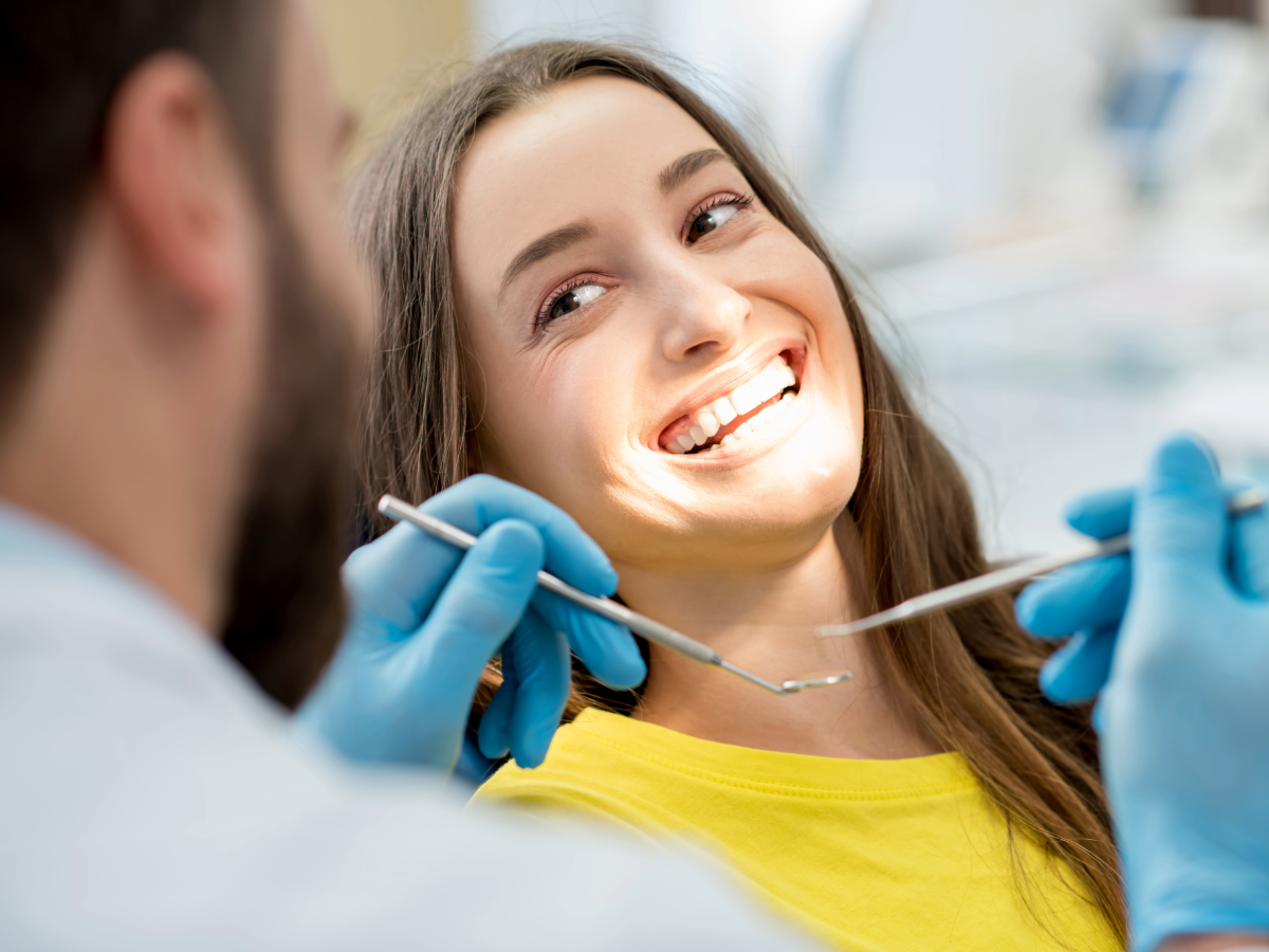 Female sitting in dentist chair smiling - for article on finding dentists in DFW for newcomers moving to DFW.