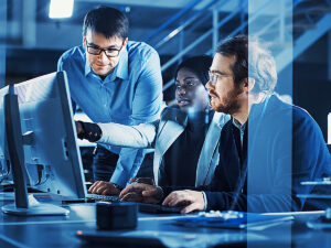 3 Coworkers looking at computer monitor in an IT technology office for article 10 Leading Technology Companies in DFW.