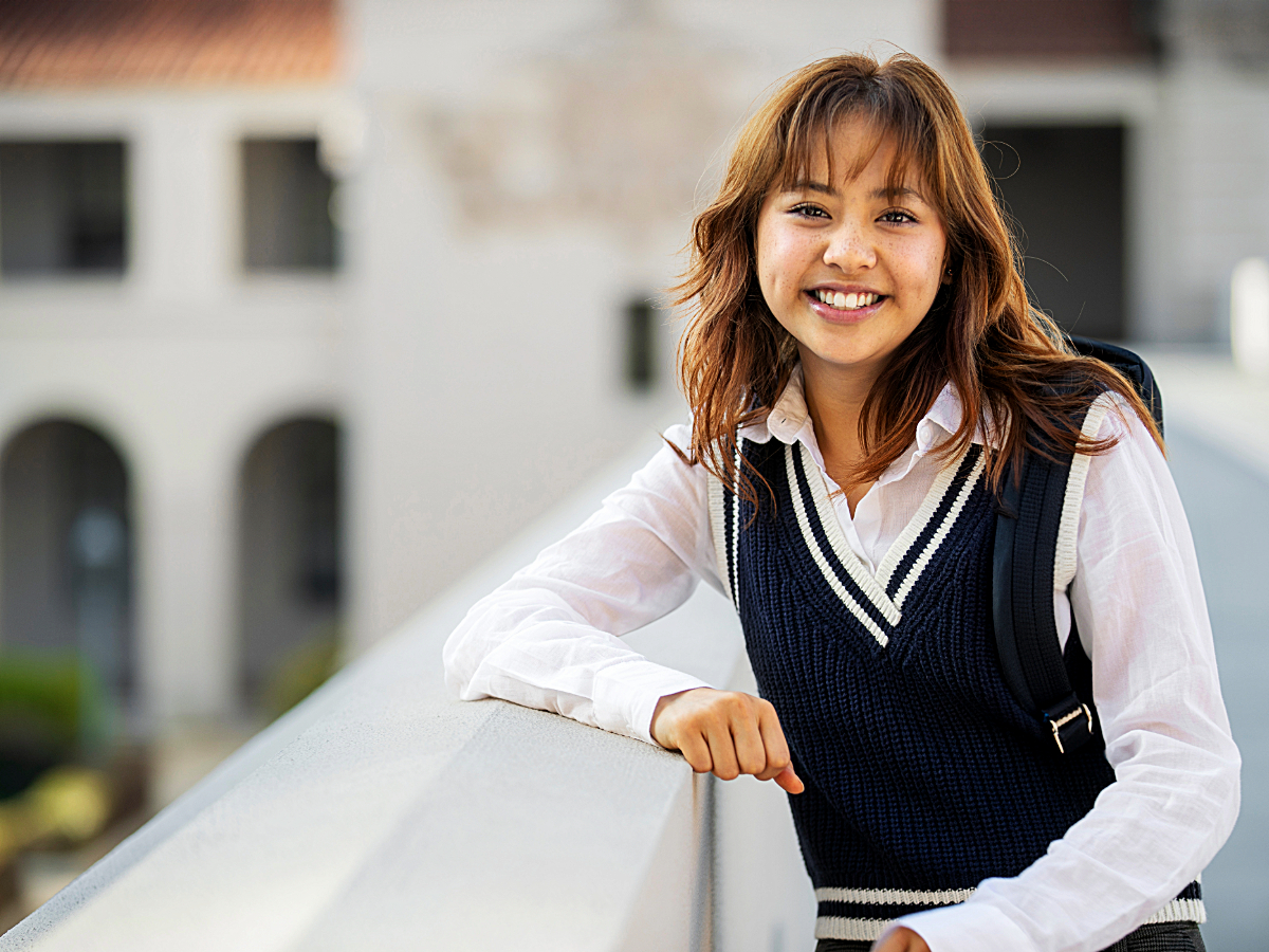 High school girl in private school uniform leaning on balcony overlooking school courtyard for article Top 4 Private High Schools in DFW for newcomers moving to DFW.