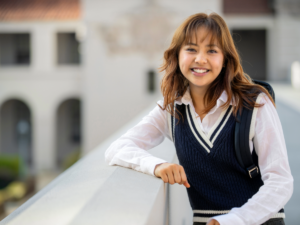 High school girl in private school uniform leaning on balcony overlooking school courtyard for article Top 4 Private High Schools in DFW for newcomers moving to DFW.