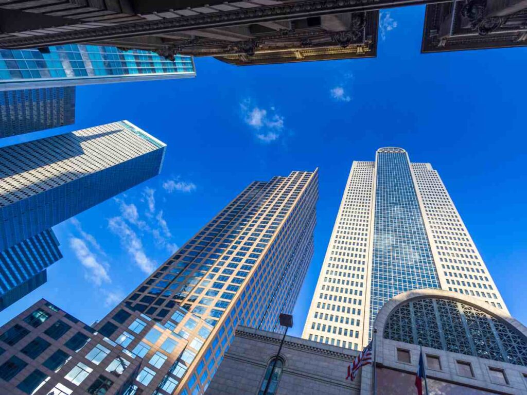 Street level view looking up at skyscrapers with blue sky behind the tops of them for article 8 Major DFW Industries and Employers for newcomers moving to DFW.