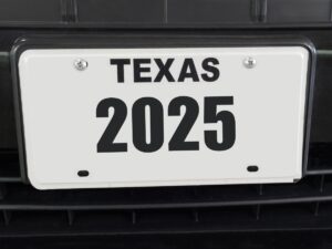 Close up of white Texas license plate that says 2025 on a black vehicle for article My Plates: Registering A Car in DFW for newcomers moving to DFW.