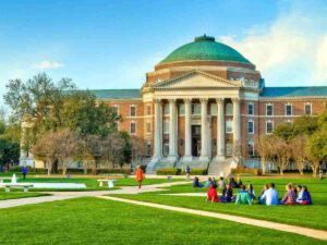 Students hanging out on bright green lawn in front of Dallas Hall at SMU for article 9 Top Colleges and Universities in Dallas-Fort Worth for newcomers moving to DFW.