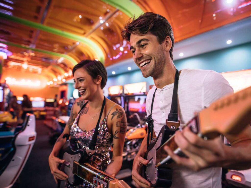 Man and woman on a date playing small guitars in an arcade for article 10 Ideas for A Unique Date Night in DFW for newcomers moving to DFW.