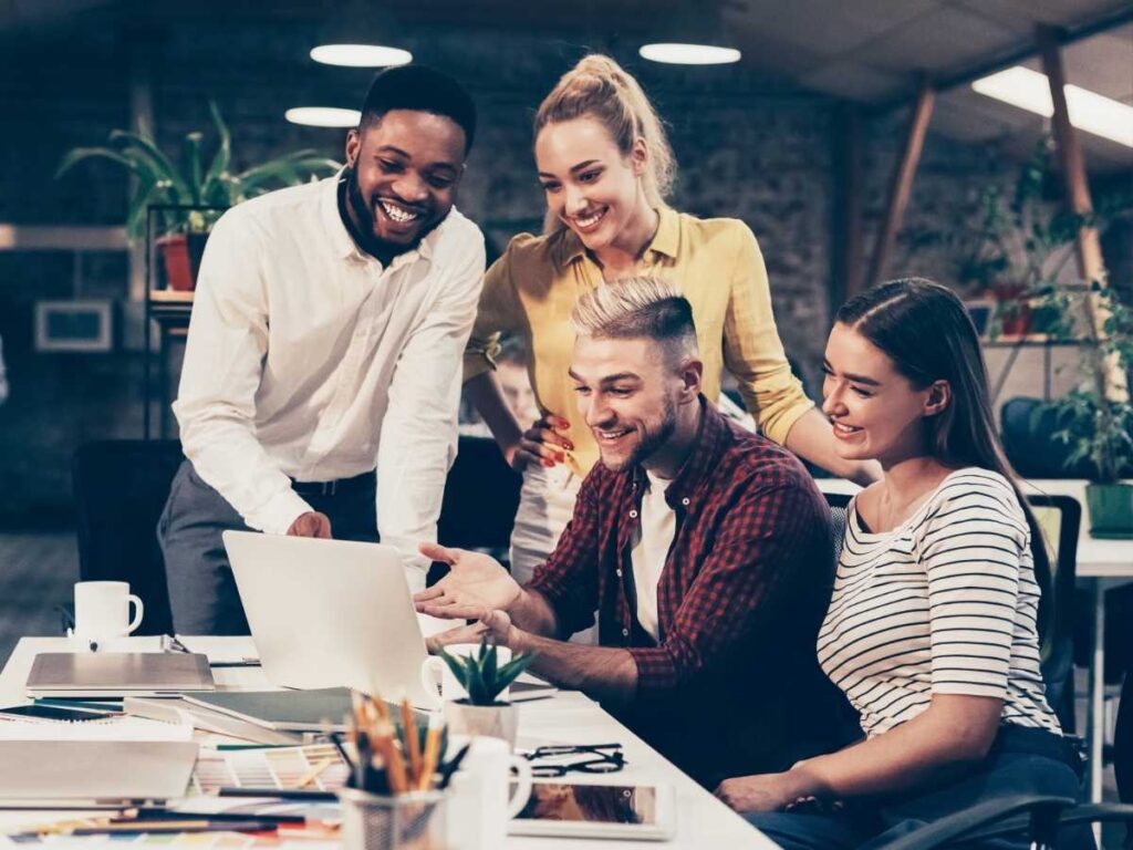 Group of young professionals around a cluttered desk looking at a laptop for article Starting a Business in DFW in 2025 for newcomers moving to DFW.